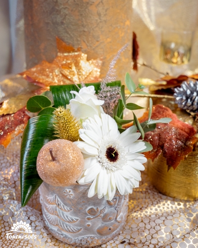 Composition florale du Nouvel An en blanc et argent avec gerbera blanc, feuillages et bougie dorée